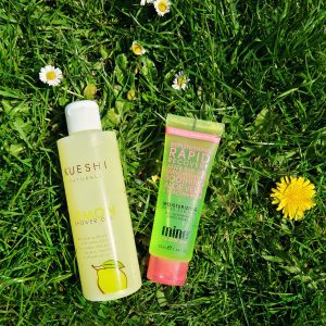 Kueshi lemon shower gel and Minetan after sun gel laid on the grass