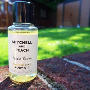 Mitchell and Peach English Leaf Body Oil bottle sat on a brick wall