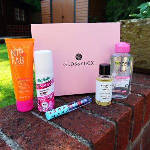 Pink glossybox with beauty products placed in front of it. The Dreaming in Paradise edition Glossybox.