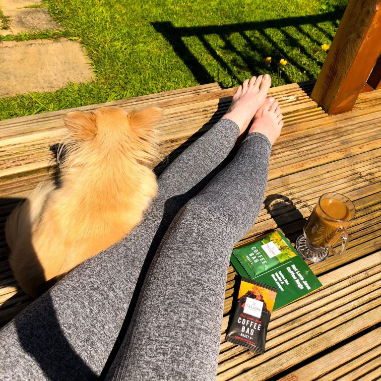 Taylors of Harrogate Coffee Bag sachets placed by the side of a cup of coffee in a glass coffee cup