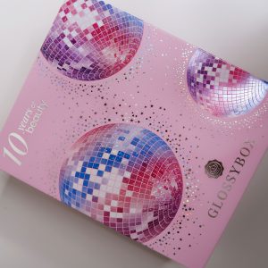 10th Birthday Edition Glossybox: Pink cardboard glossbox with pink, purple, blue and silver disco balls across the front