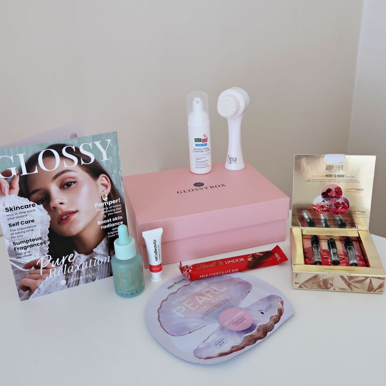 Collection of beauty products sat on top of a table featuring a pink glossybox. 